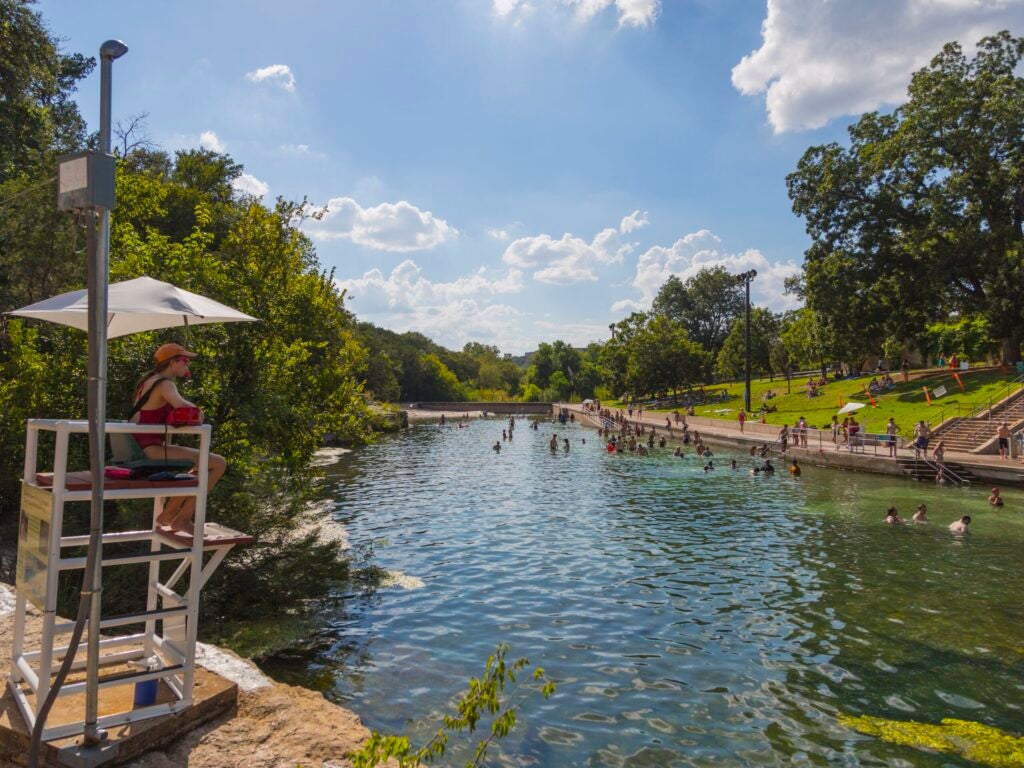 A lifeguard watches the swimmers enjoying Barton Springs Pool on a sunny day