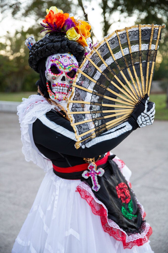 A women with a decorative painted face like a skeleton and a traditional dress in honor of la Catrina