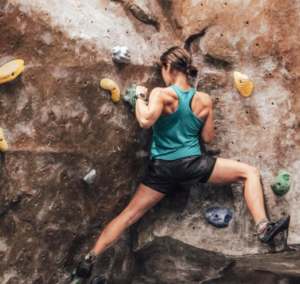 Woman climbing indoor rock climbing wall. 