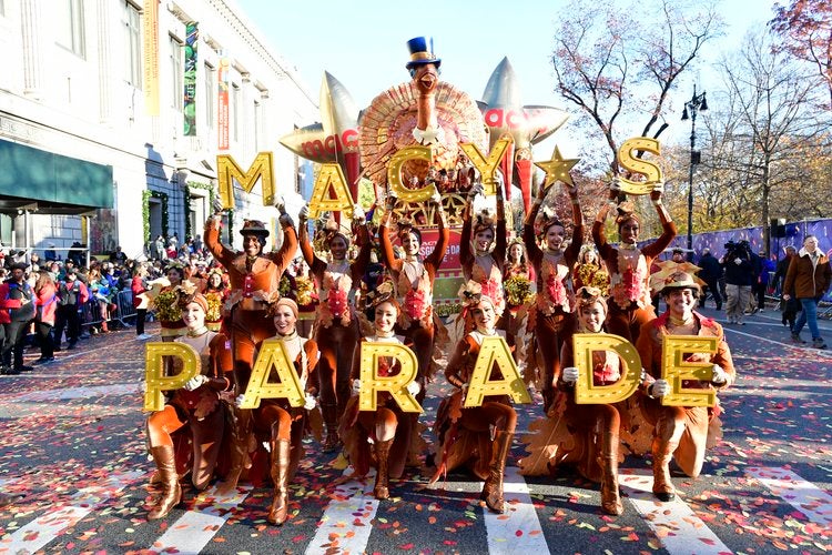 Macy's Day Parade participants spell out the event name