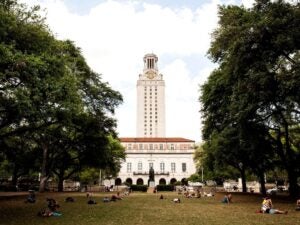 UT tower with path lined with trees and Washington statue in the foreground.