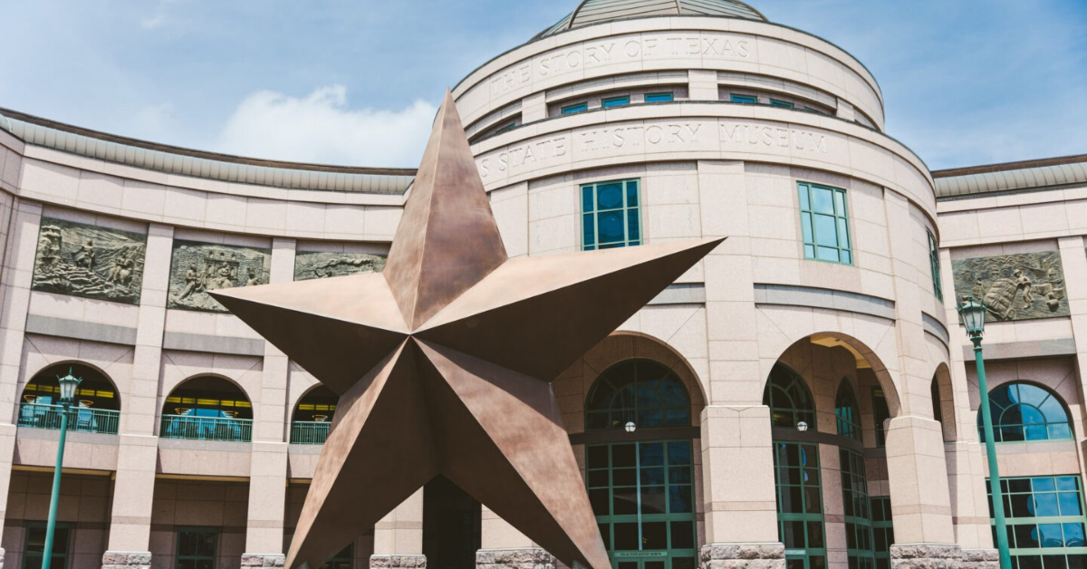 Large bronze star sculpture in front of the Bullock Texas State History Museum with arched windows and historical friezes.