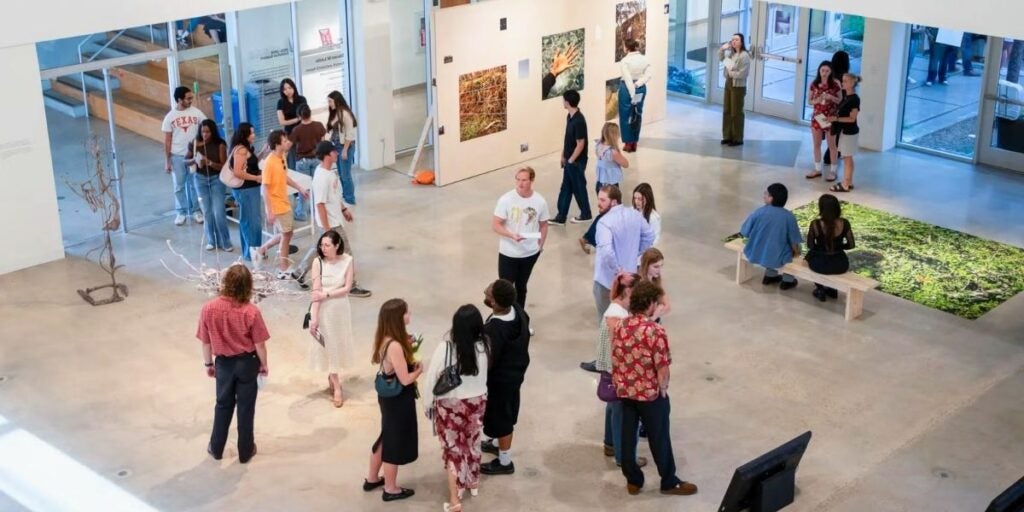 People viewing artwork in a modern gallery space with concrete floors at the UT Austin Visual Arts Center.