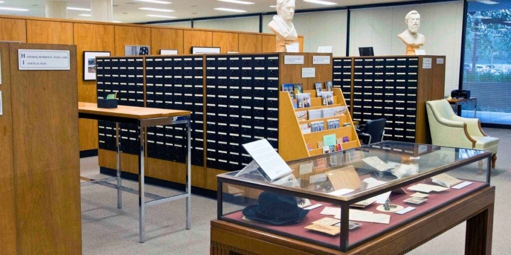 UT Austin Dolph Briscoe Center for American History interior with wooden card catalog, busts, a glass display case, and a cream armchair.