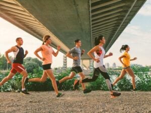 Five people jogging under a bridge