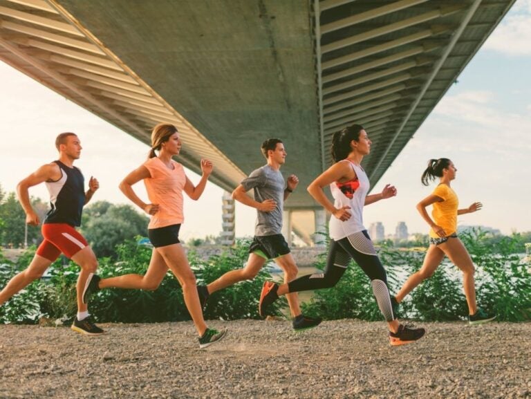 Five people jogging under a bridge