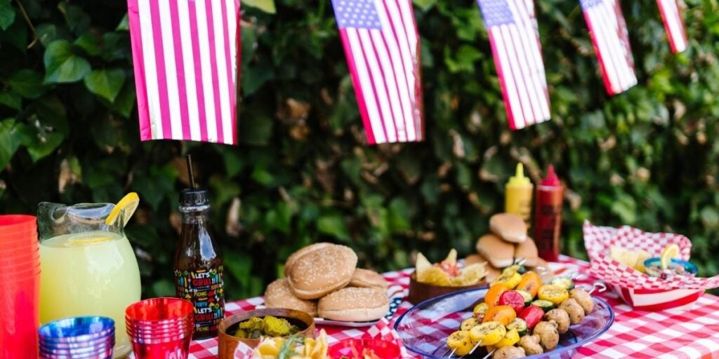 Outdoor picnic table with food and American flags.